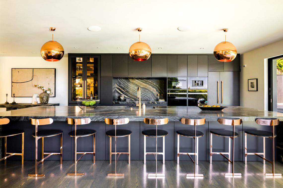 The kitchen is “pure drama” with a large stone island and modern light fixtures like floating works of art, the listing states.