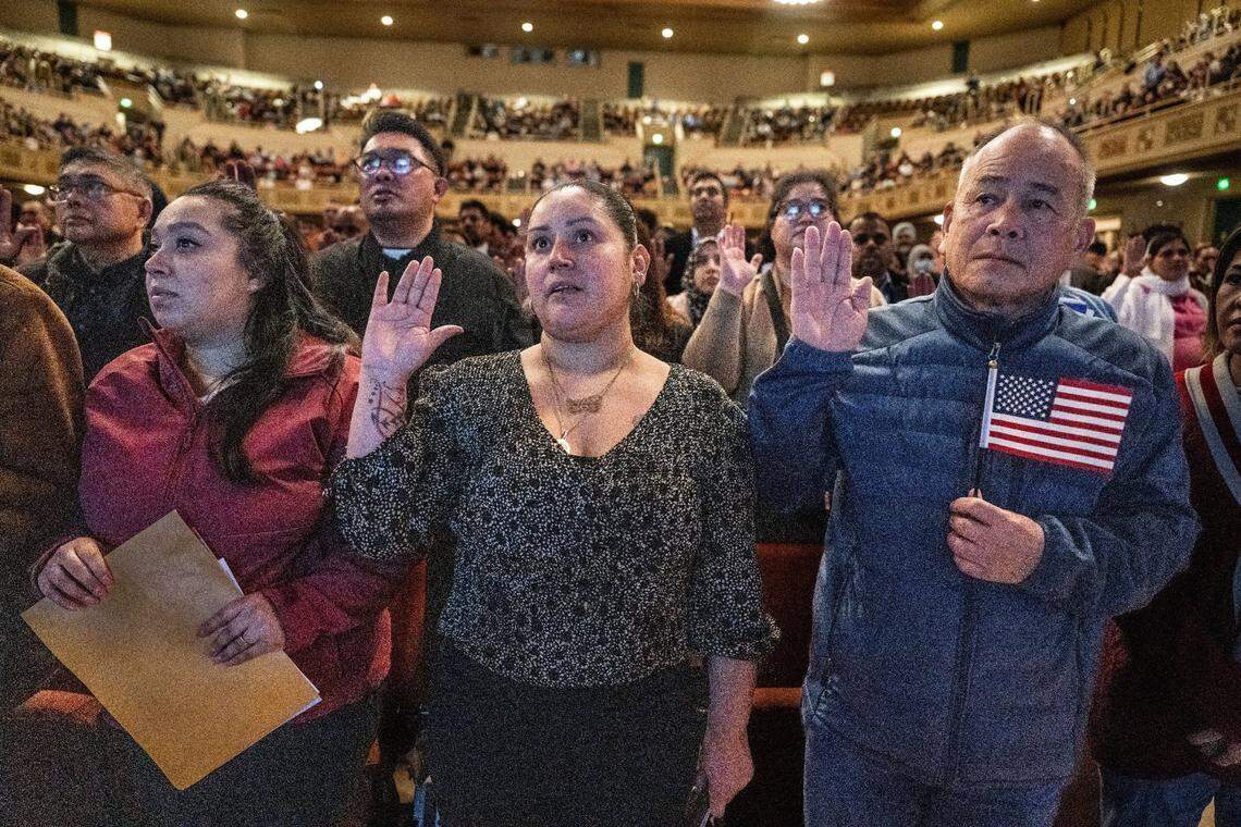 Stockton resident Sandra Bermudez, center, originally from Mexico, and Elk Grove resident Tan Nguyen, originally from Vietnam, join more than 800 other people to take the oath during a naturalization ceremony to become U.S. citizens on Wednesday at the Memorial Auditorium in Sacramento.