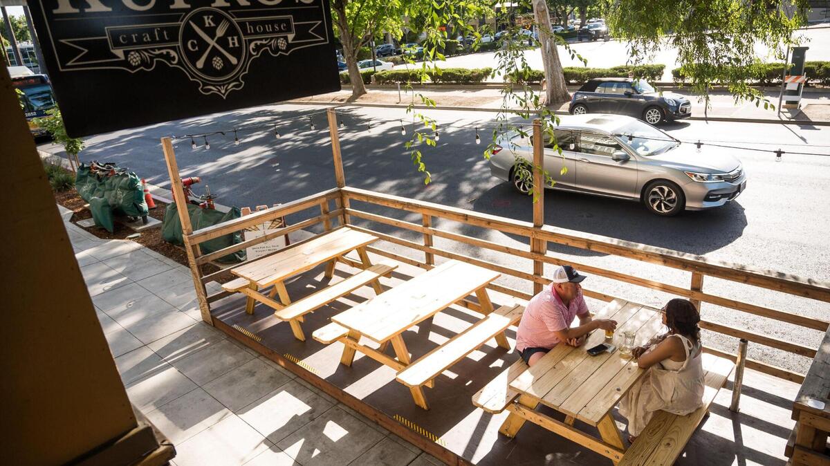 Regulars Samara Palko, right, and husband Pater Palko, midtown Sacramento residents for 19 years, enjoy drinks in Kupros Craft House’s outdoor parklet in May 2023, on 21st Street.