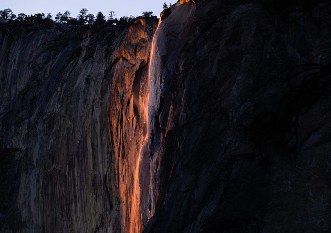 The wispy flow of Horsetail Fall is illuminated by the setting sun in Yosemite Valley on Sunday, Feb. 9, 2025, creating the firefall effect that draws a surge of visitors.