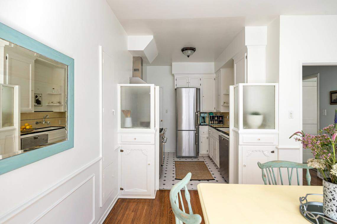 The remodeled kitchen features original cabinetry, vintage tile, and European appliances beside a formal dining area.