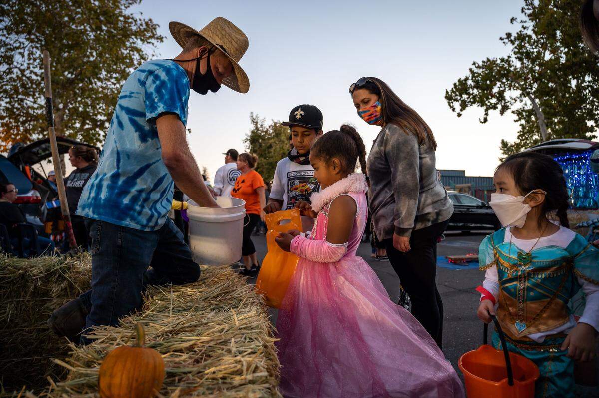 Florence Markofer Elementary School student Amena Beshears, 6, center, collects candy from fourth-grade teacher Leon Vanderspek, who has a farm-themed Halloween display, at the parent teacher organization’s Trunk or Treat fundraiser Oct. 15 at the school in Elk Grove. It was the PTO’s first fundraiser in that style, which featured Halloween costumes, food, teacher-decorated displays, music and dancing.