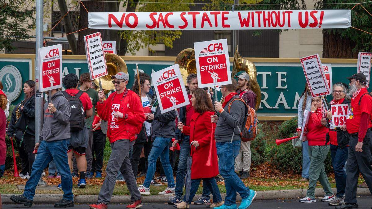Strikers march at the entrance to the Sacramento State campus on J Street on Thursday, Dec. 7, 2023. The California Faculty Association, which represents about 29,000 professors, lecturers, librarians, counselors and coaches across the CSU system, is staging one-day strikes at multiple campuses this week.