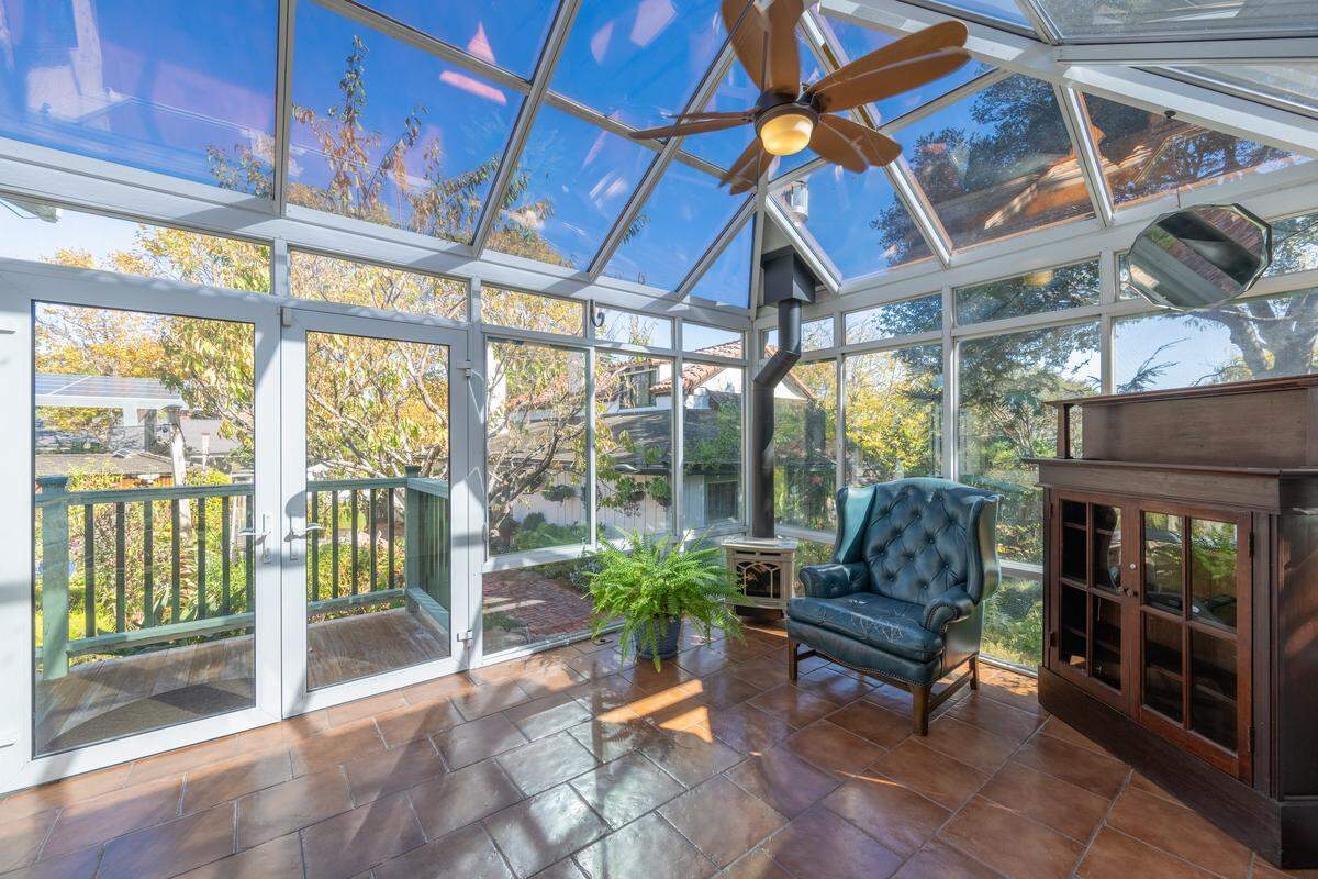 Sunlight streams into the Monterey cottage’s charming greenhouse room, creating an ideal retreat for gardening enthusiasts or a peaceful spot to relax year-round.