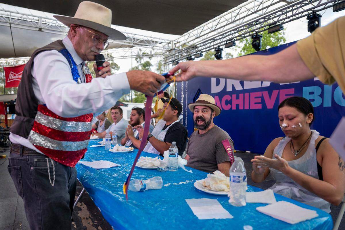 Dennis Forel prepares to hand the first place ribbon to Matthew Ampersand after competing in the adult division of the California State Fair’s pie eating contest in Sacramento on Monday.