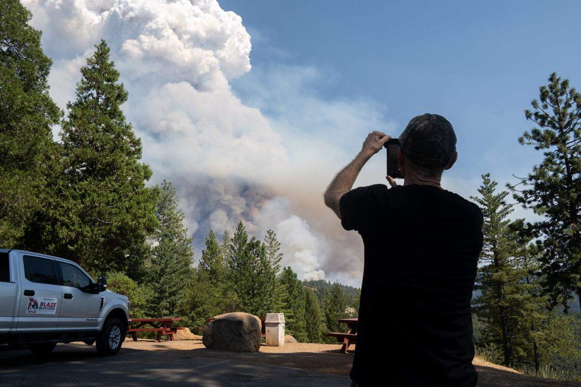 Foresthill resident Fred Poiesz watches air tankers drop fire retardant from Worton’s Market in Foresthill as smoke from the Mosquito Fire fills the sky on Wednesday. He evacuated last night and hopes his home wont burn.