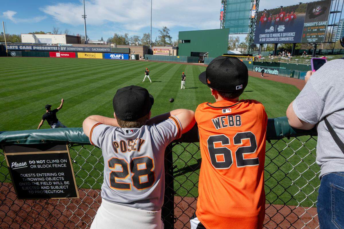 San Francisco Giants fans Ryland Stewart, 9, left, and his friend Logan Barajas, 9 of Woodland, watch as the ball players warm up before an exhibition game against the Sacramento River Cats at Sutter Health Park on Sunday, March 23, 2025, in West Sacramento.