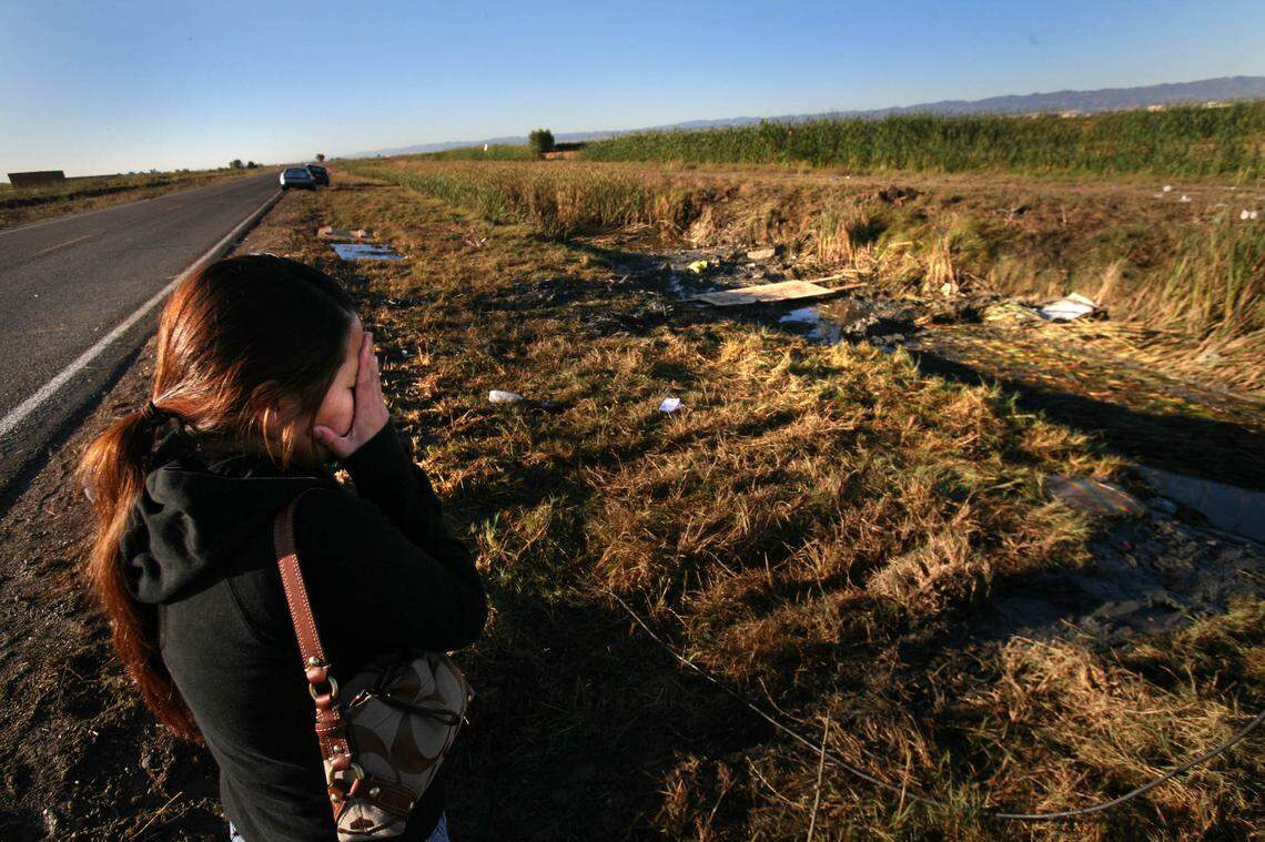 Cher Vang covers her face at the bus crash site the day after it happened. She came to look for her mother, Khou Yang, who was killed in the crash.
