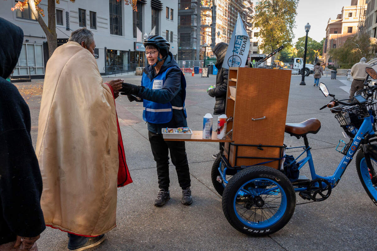 Sister Libby Fernandez with Mercy Pedalers gives out coffee and supplies to people experiencing homelessness Friday, Nov. 10, in downtown Sacramento in front of the Cathedral of the Blessed Sacrament.