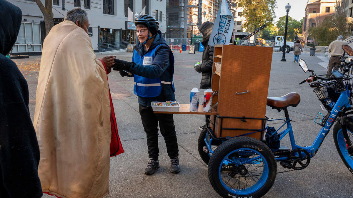 Sister Libby Fernandez with Mercy Pedalers gives out coffee and supplies to people experiencing homelessness Nov. 10, in downtown Sacramento in front of the Cathedral of the Blessed Sacrament. The Mercy Pedalers are asking Book of Dreams readers for additional adult trikes for their volunteers to reach more people in need as well as sleeping bags, socks and other supplies.