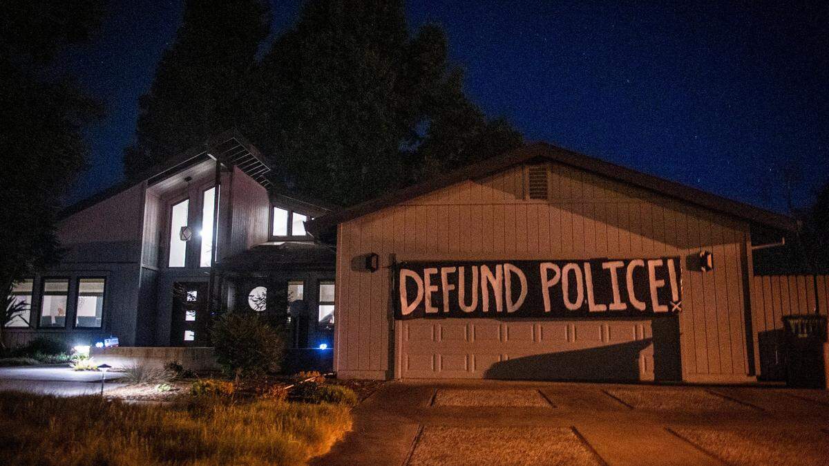 A “defund police” banner hangs on Sacramento Mayor Darrell Steinberg’s garage during a June block party protest.
