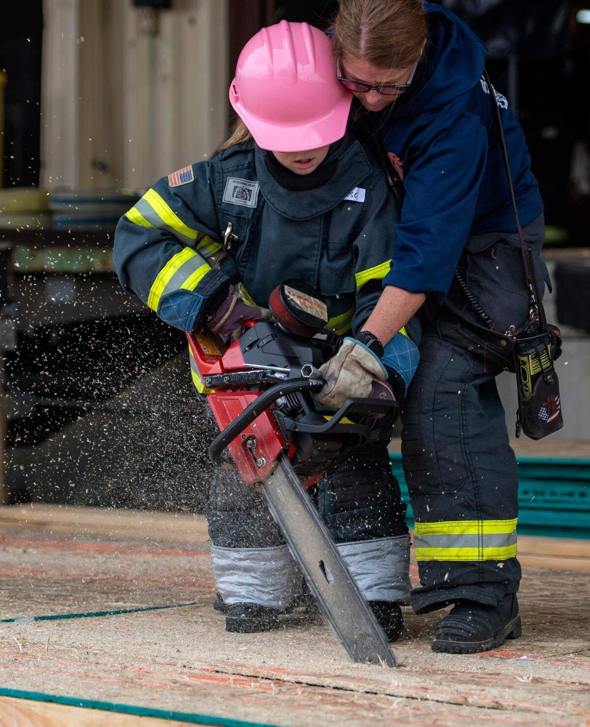 Sacramento Fire Department Capt. Erika Enslin assists Reese Blankenship, 10, with the chain saw at one of the stations at the Sacramento Area Girls Fire Camp at McClellan Park on Saturday, Oct. 23, 2021.