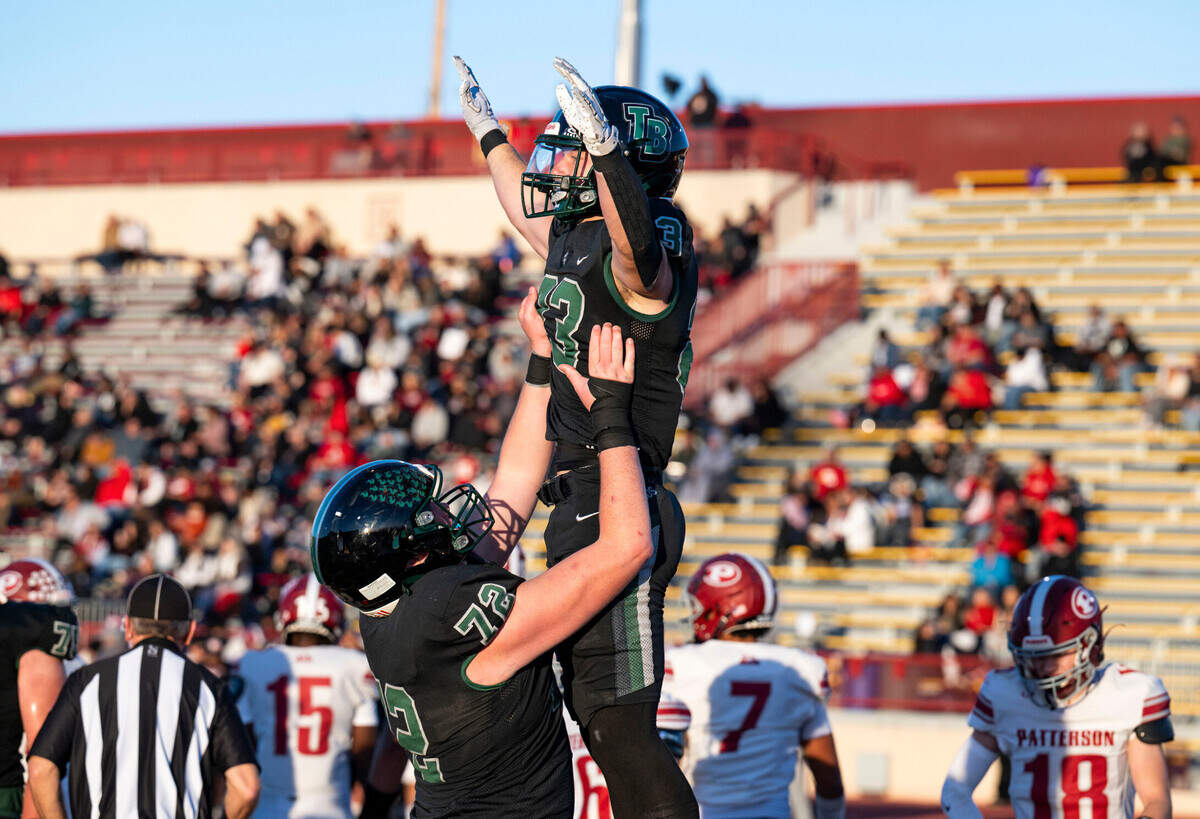 Twelve Bridges Raging Rhinos offensive lineman Caleb Amos (72) lifts running back Braeden Ward (23) into the air to celebrate a touchdown against the Patterson Tigers during the 2024 Sac-Joaquin Section Division IV championship game at Hughes Stadium.