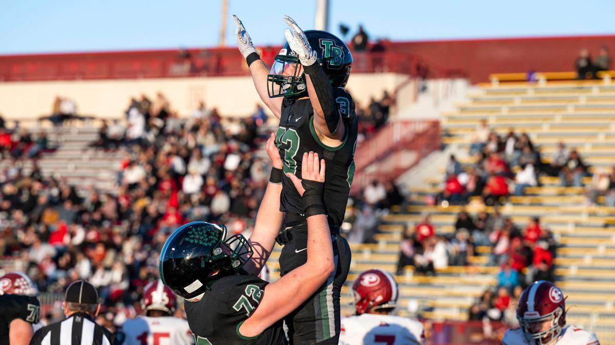 Twelve Bridges Raging Rhinos offensive lineman Caleb Amos (72) lifts running back Braeden Ward (23) into the air to celebrate a second quarter touchdown against the Patterson Tigers during the Sac-Joaquin Section Division IV championship game at Hughes Stadium in Sacramento on Friday.