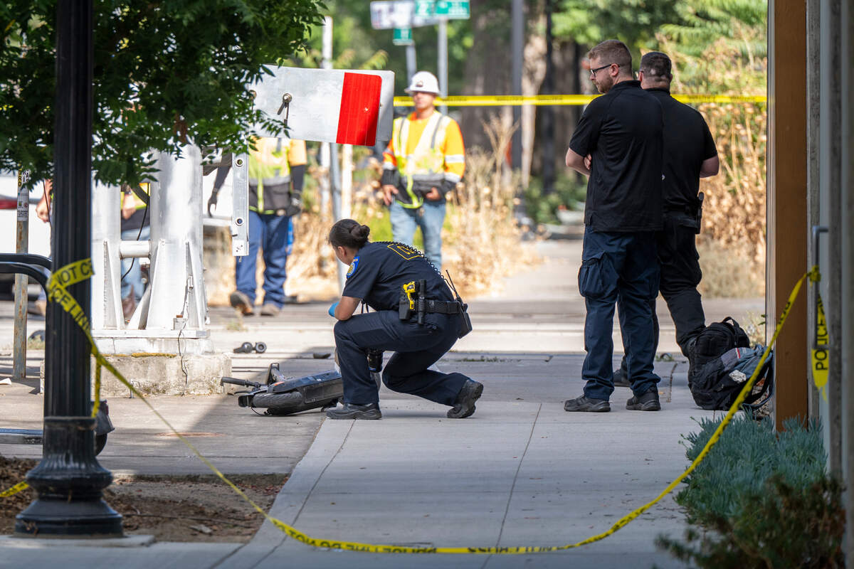 A Sacramento police crime scene investigator examines a scooter after a man was struck and killed by a light rail train while riding an electric scooter in midtown Sacramento on Monday.