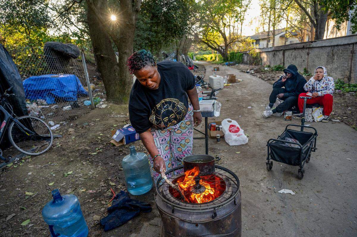 As the sun goes down in South Natomas, Elizabeth Williams stirs a fire before deep-frying dinner for fellow homeless campers on March 26. “I actually want to open up my own business called J&J’s Homeless Bar and Grill,” she said. “I want to open up a restaurant, so I’ve been looking into trying to go back to school and get my GED.”