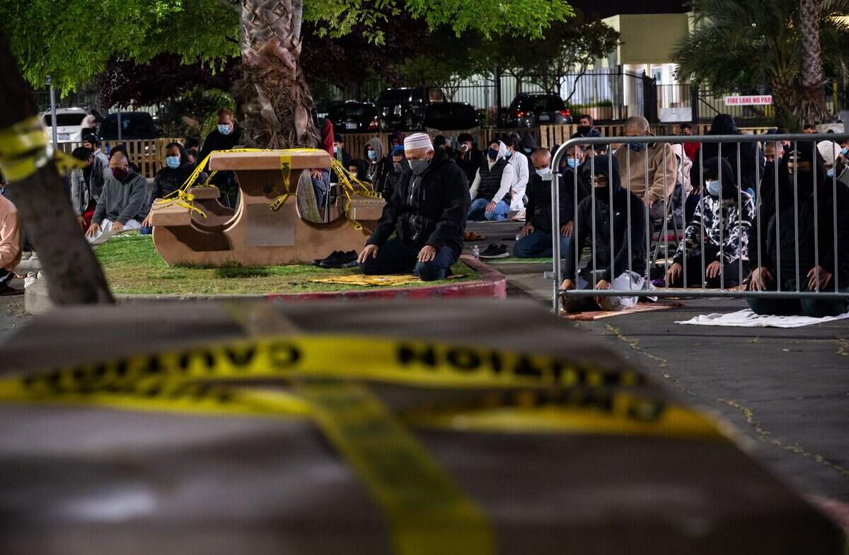 In a sectioned off part of the parking lot at Masjid Annur Islamic Center in south Sacramento, worshippers wear masks and are distanced more than usual after the first day of fasting for Muslims during Ramadan on Tuesday. Muslims fast during the holy month from dawn to sunset, then often break fast together. This year, the picnic tables are wrapped in caution tape because of the pandemic.