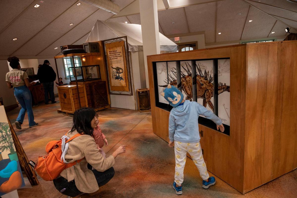 Fairtytale Town visitors check out the dinosaur exhibit inside the newly unveiled Story Center on Saturday.