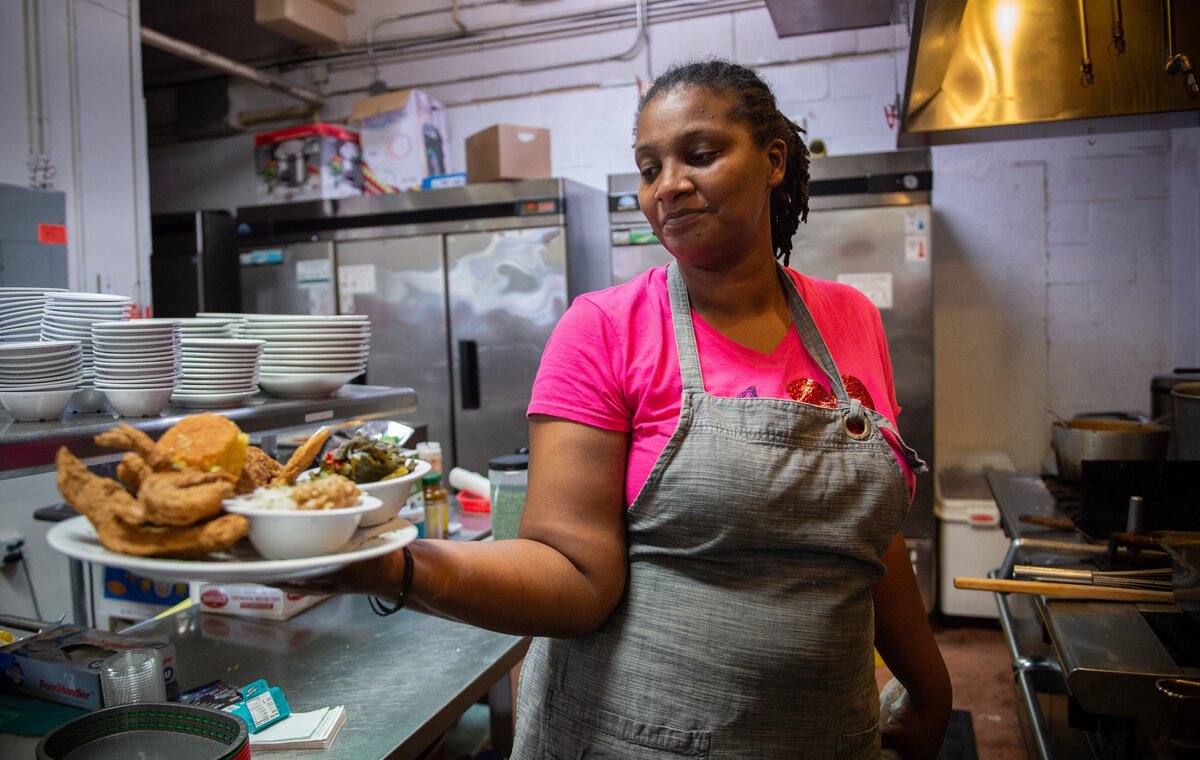 Tamar McCree holds up a combination plate of soul food made in the kitchen at CoLo’s Soul Food & Seafood on Del Paso Boulevard in 2020.