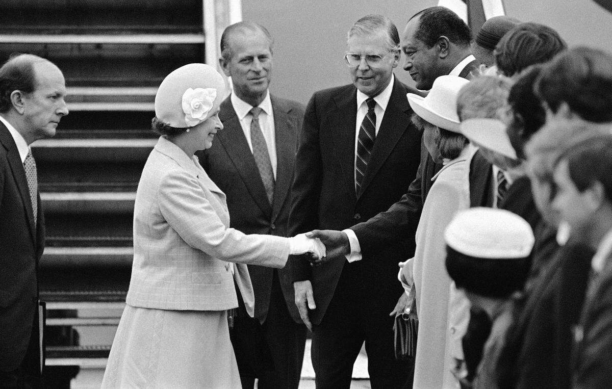 Queen Elizabeth II, with Prince Philip in the background, shakes hands with Los Angeles Mayor Tom Bradley after she arrived at Long Beach Airport in afternoon on Sunday, Feb. 27, 1983.