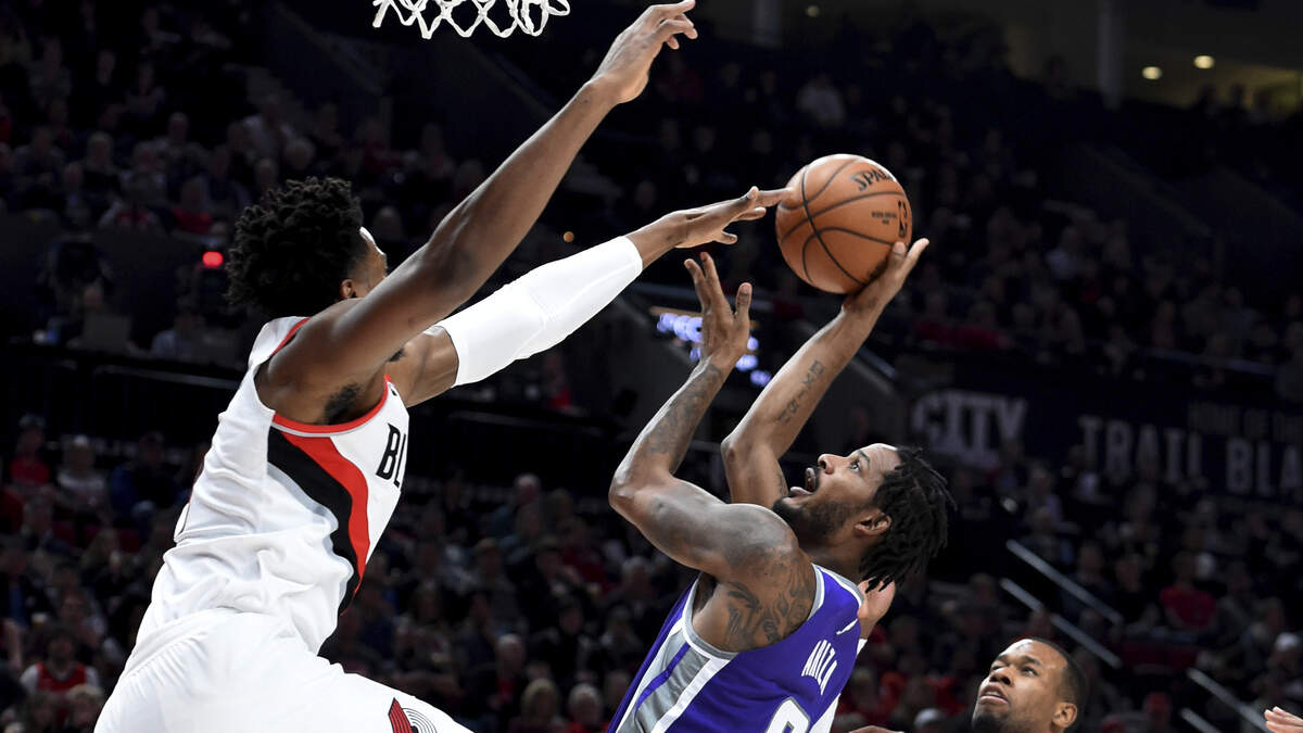 Sacramento Kings forward Trevor Ariza, center, shoots the ball over Portland Trail Blazers center Hassan Whiteside, left, as guard Rodney Hood, right, closes in during the first half of an NBA basketball game in Portland, Ore., Wednesday, Dec. 4, 2019. (AP Photo/Steve Dykes)