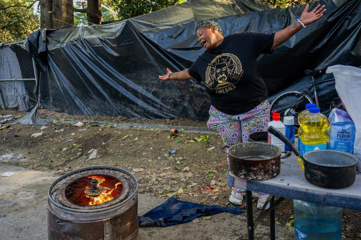 Elizabeth Williams uses a bicycle wheel for a makeshift grill to cook dinner for other homeless members of her encampment on March 26 in South Natomas. When she was arrested and placed in jail in February, the police threw away her gas grill and all her belongings. “They took everything we got,” she said.