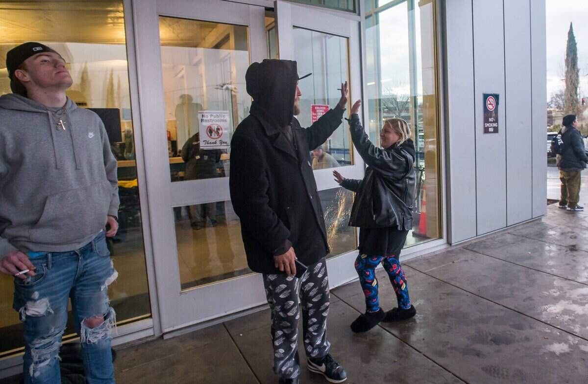 Barbara Frederick, who is trying to return to Oregon after visiting California for her birthday, is thanked by fellow stranded traveler Michael Marker outside the Greyhound Bus Station on Richards Boulevard in Sacramento, as Arkansas native Dustin Combs waits at left, on Tuesday, Feb. 28, 2023, while winter weather inundated much of the region. “This morning I woke up and I was hungry … with a sleepless night on the floor, I looked around and I didn’t only think of me,” Frederick said, adding she reached out to city law enforcement and firefighters to ask for assistance for the stranded travelers. The city’s Office of Emergency Management and American Red Cross worked to supply blankets and overnight essentials, and hot meals were provided by Hop Gardens restaurant.