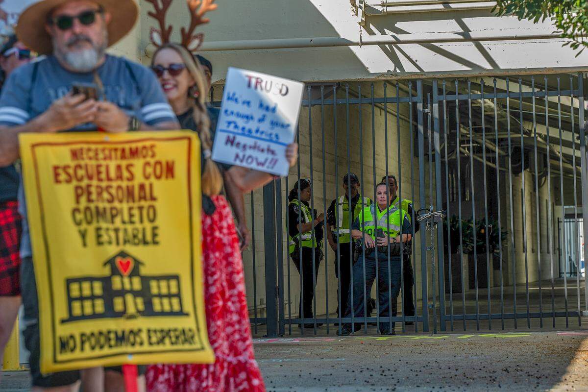 Security guards watch from behind a gate as more than 1,000 teachers and parents rally at the Twin Rivers Unified School District office Friday as the teacher strike reached its 12th day of instruction. 