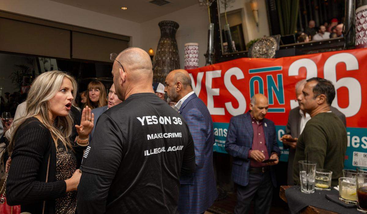 Proposition 36 supporters Abby Reisig, left, and Garrett Hamilton, wearing a “make crime illegal again” shirt, talk before results are announced during an Election Night party at Zócalo in midtown Sacramento on Tuesday.