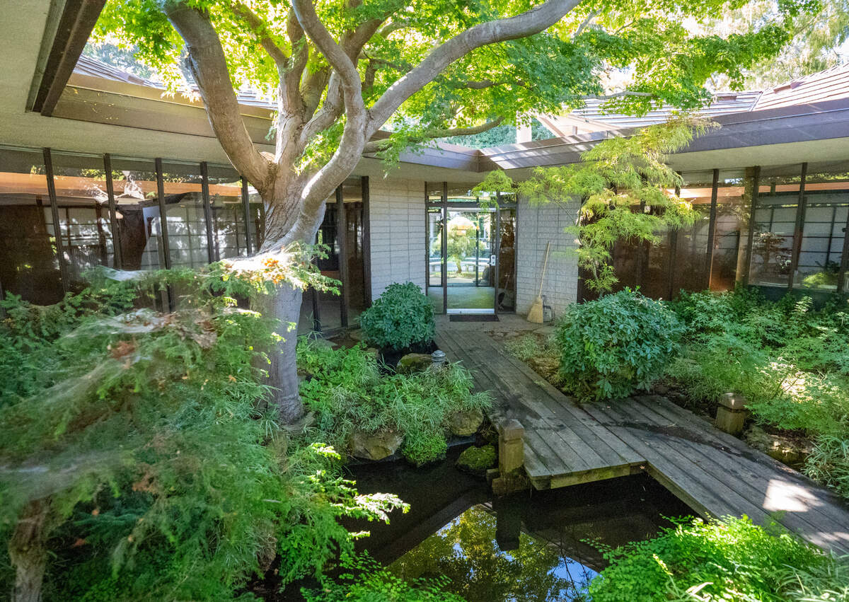 The residence at 523 Grosevnor Court is entered through a peaceful front courtyard, where a wood bridge crosses a rock and water pond and leads to the full-glass front door, October 20, 2022.