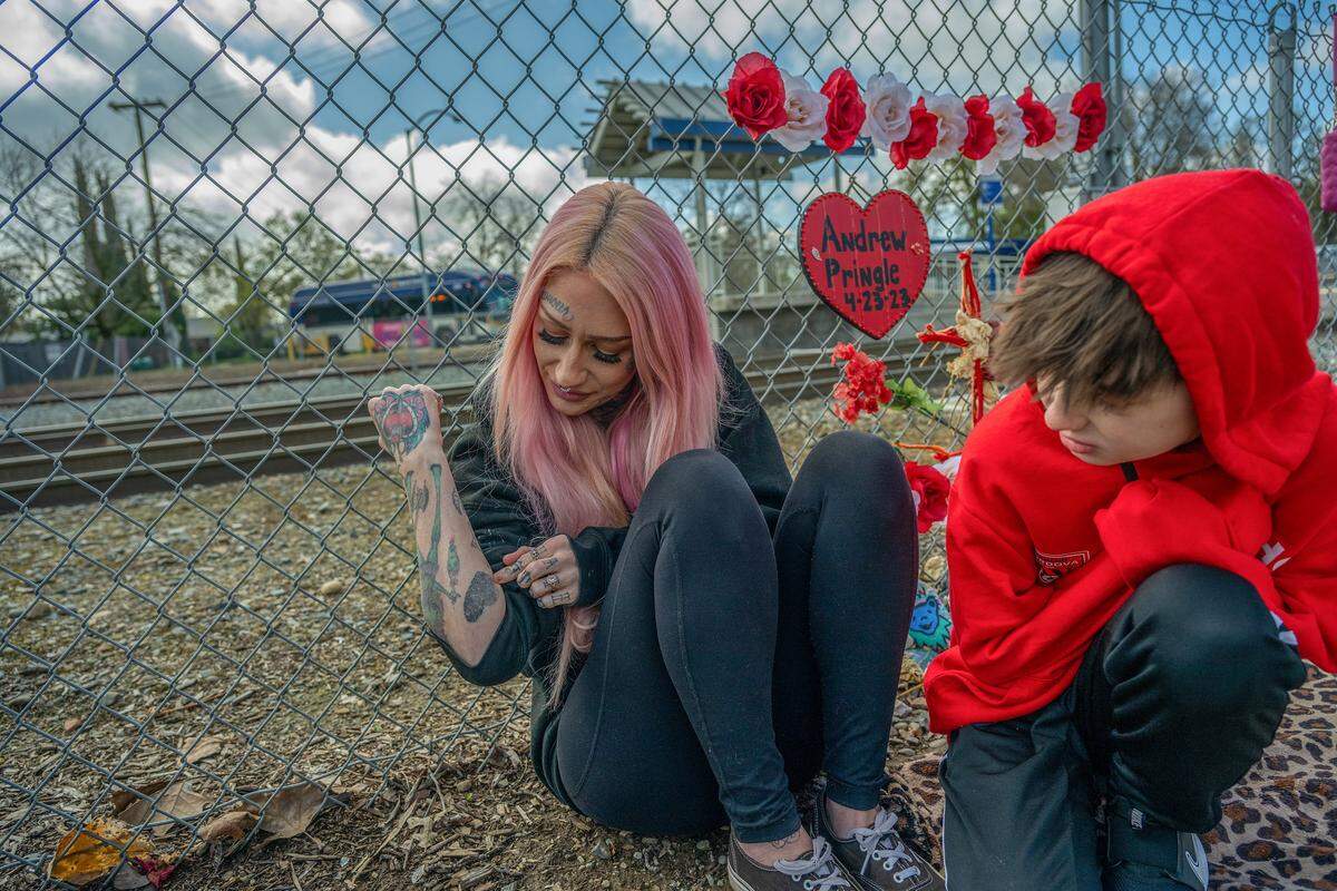 Erika Pringle shows a heart tattoo of her brother Andrew Pringle’s fingerprint, with a trace of his ashes mixed into the ink, to her son Ryley French, 10, in March. After his death, she and her sisters all got matching tattoos.