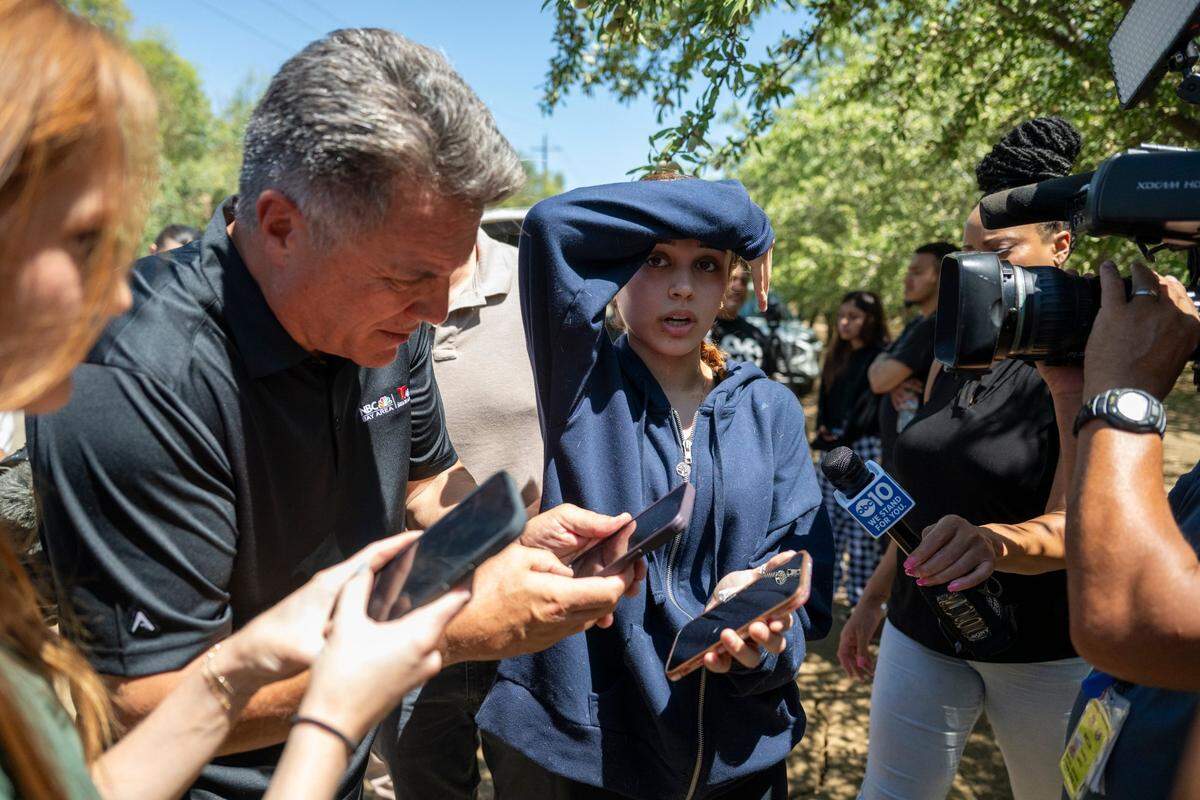 Syanna Ruiz, center, displays a photograph on her boyfriend Jesus Ramos on her cellphone on Wednesday to reporters at the road closure near the Esparto fireworks facility that exploded the night before. Ramos was working at the site.
