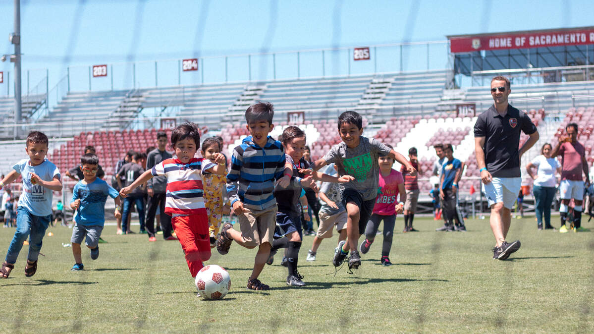 Children hit the field with a game of their own, sandwiched between the adult teams, at a refugee soccer tournament organized by World Relief Sacramento.