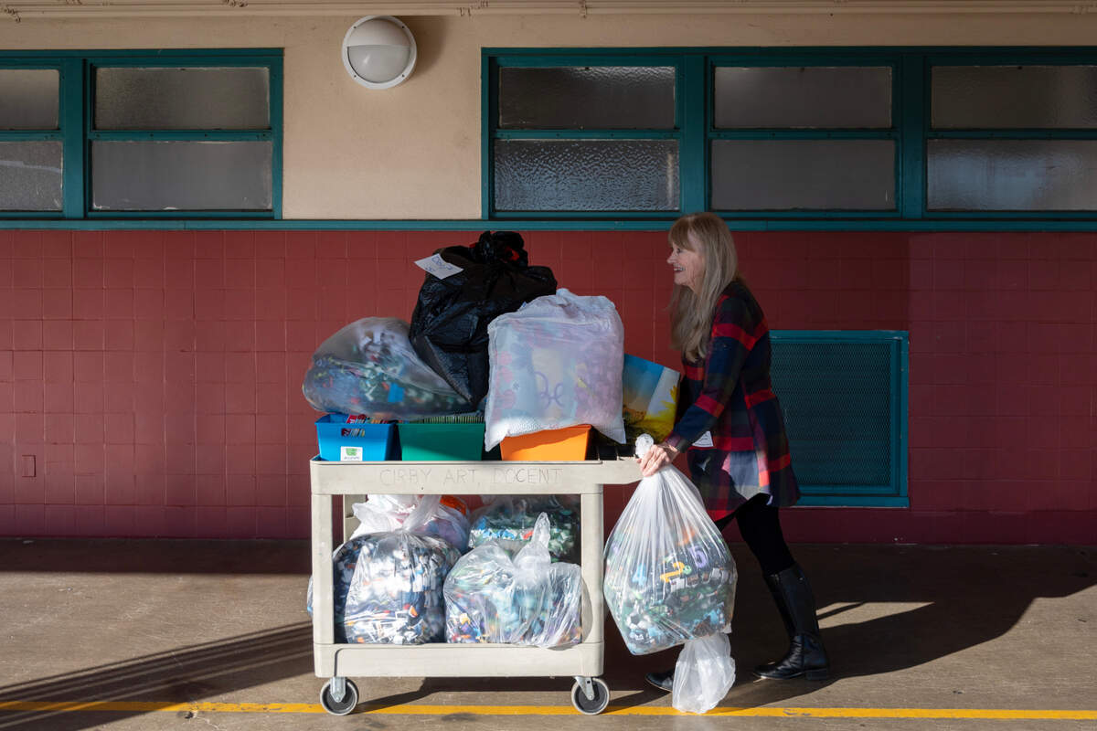 Donja Garvey, of the non-profit My Mother’s Voice, carts in books and blankets for students at Cirby Elementary School in Roseville on Friday, Nov. 18, 2022.