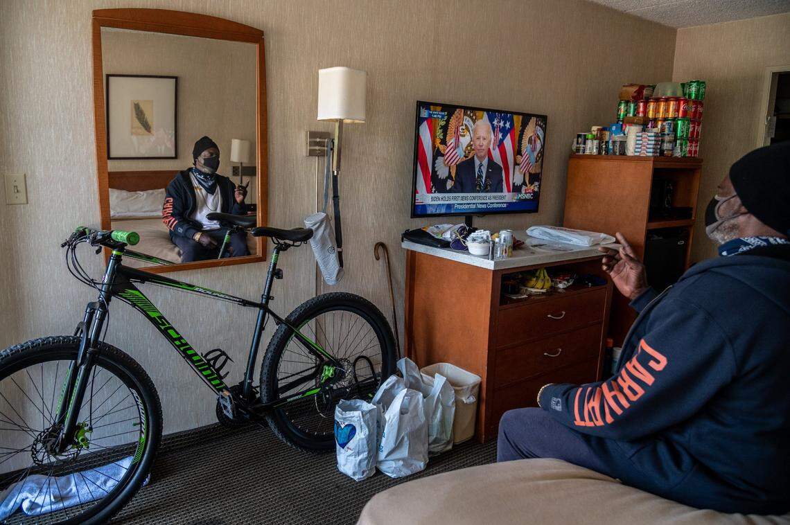 After living in a homeless encampment on the river for ten years, Bennie Rogers, 68, watches President Biden’s first press conference inside the Vagabond Inn where he found temporary housing through Project Roomkey on Thursday, March 25. Now he stockpiles cans of soda and food, has a shower, and is able to store his things and not worry about them being stolen.