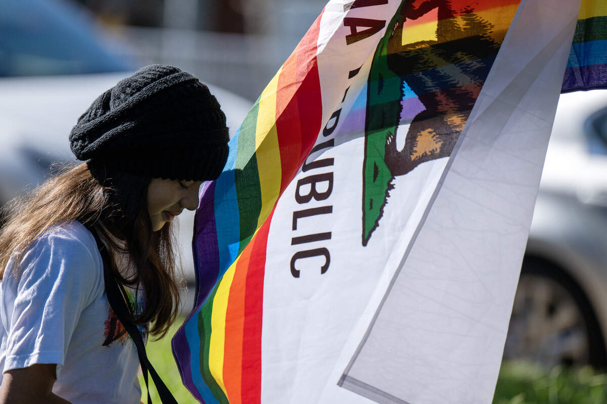 Clementine McDaniel of Rancho Cordova gathers her things near a California pride flag at the inaugural Folsom Family Pride Celebration at Folsom City Lions Park on Saturday, Oct. 11, 2025.