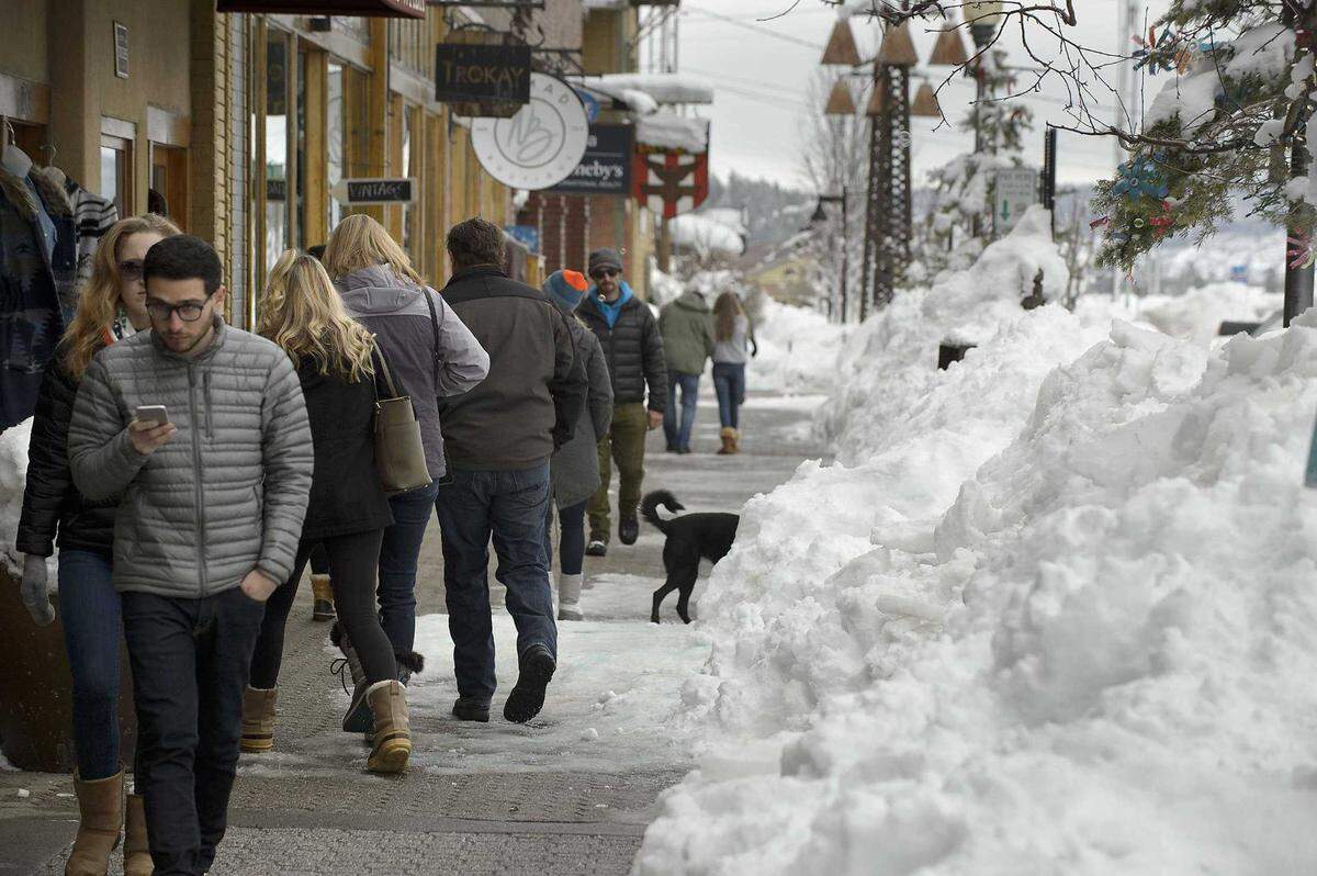 Shoppers walk along the sidewalk beside the snow piled up along Donner Pass Road in central Truckee in 2017.
