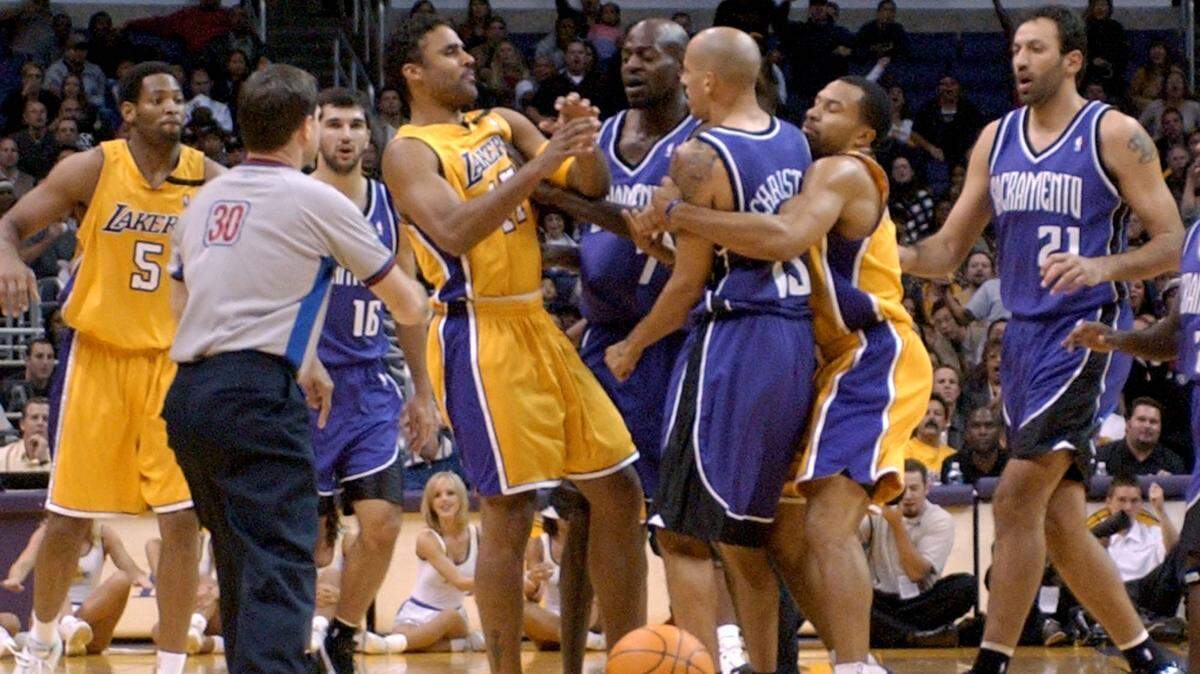 Sacramento Kings guard Doug Christie, center right, is held back by Los Angeles Lakers guard Derek Fisher during a scuffle with Lakers forward Rick Fox, center left, after a foul by Fox on Christie during the first half of a preseason game on Oct. 25, 2002, in Los Angeles. Both players were ejected from the game.