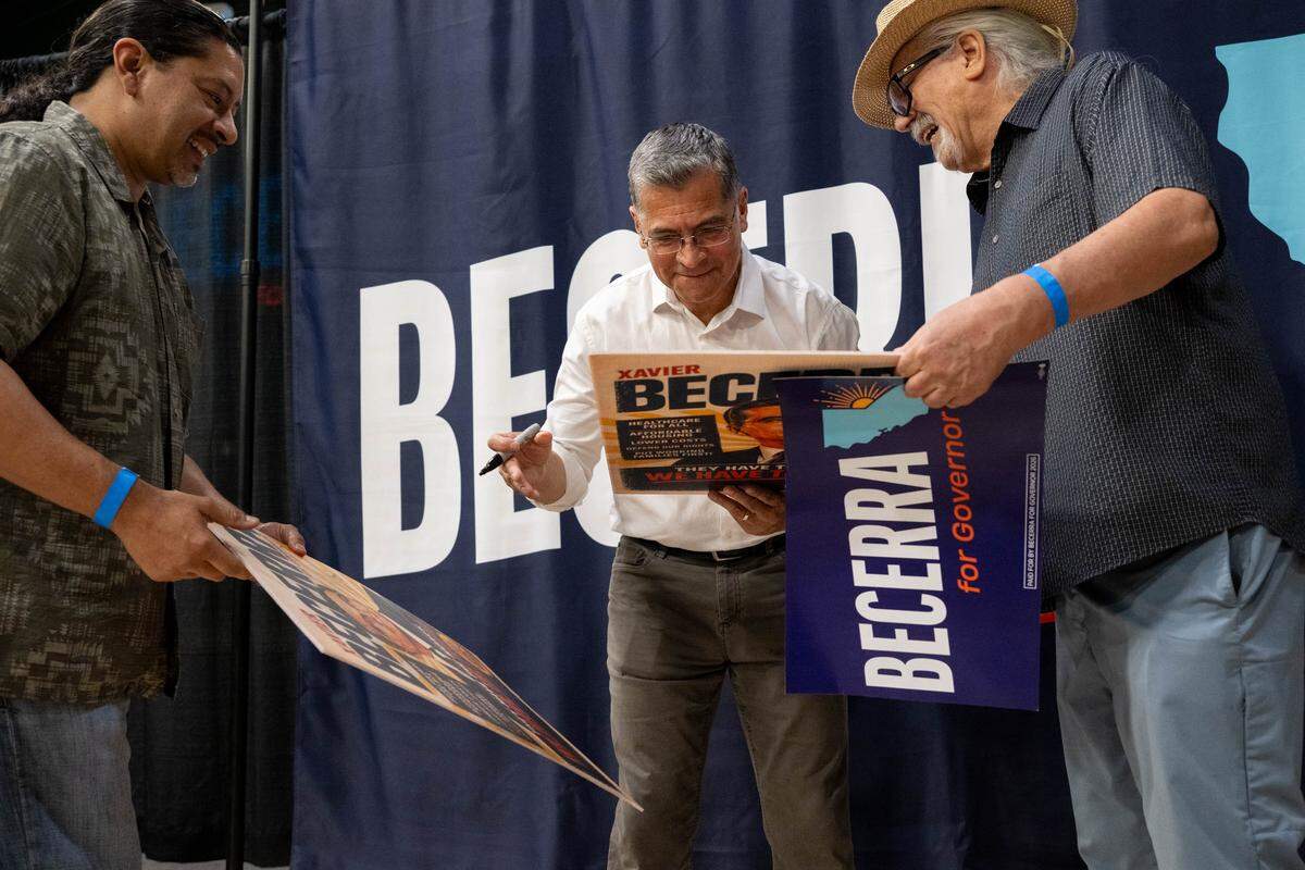 Gubernatorial candidate Xavier Becerra autographs posters for supporters Rafael Aguilera and Tony Perez after a hometown rally at Sacramento State on Monday.
