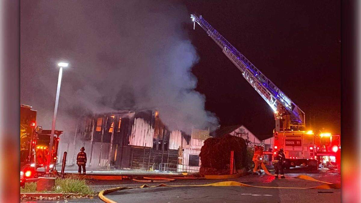 Firefighters use a ladder truck to extinguish flames at the site of a commercial structure fire near Highway 49 and Hulbert Way in North Auburn on Tuesday, Nov. 18, 2025. Authorities say a 34-year-old woman was arrested on suspicion of arson after she was seen walking out of the historic building, which was once part of the Cal Ida Lumber Mill.