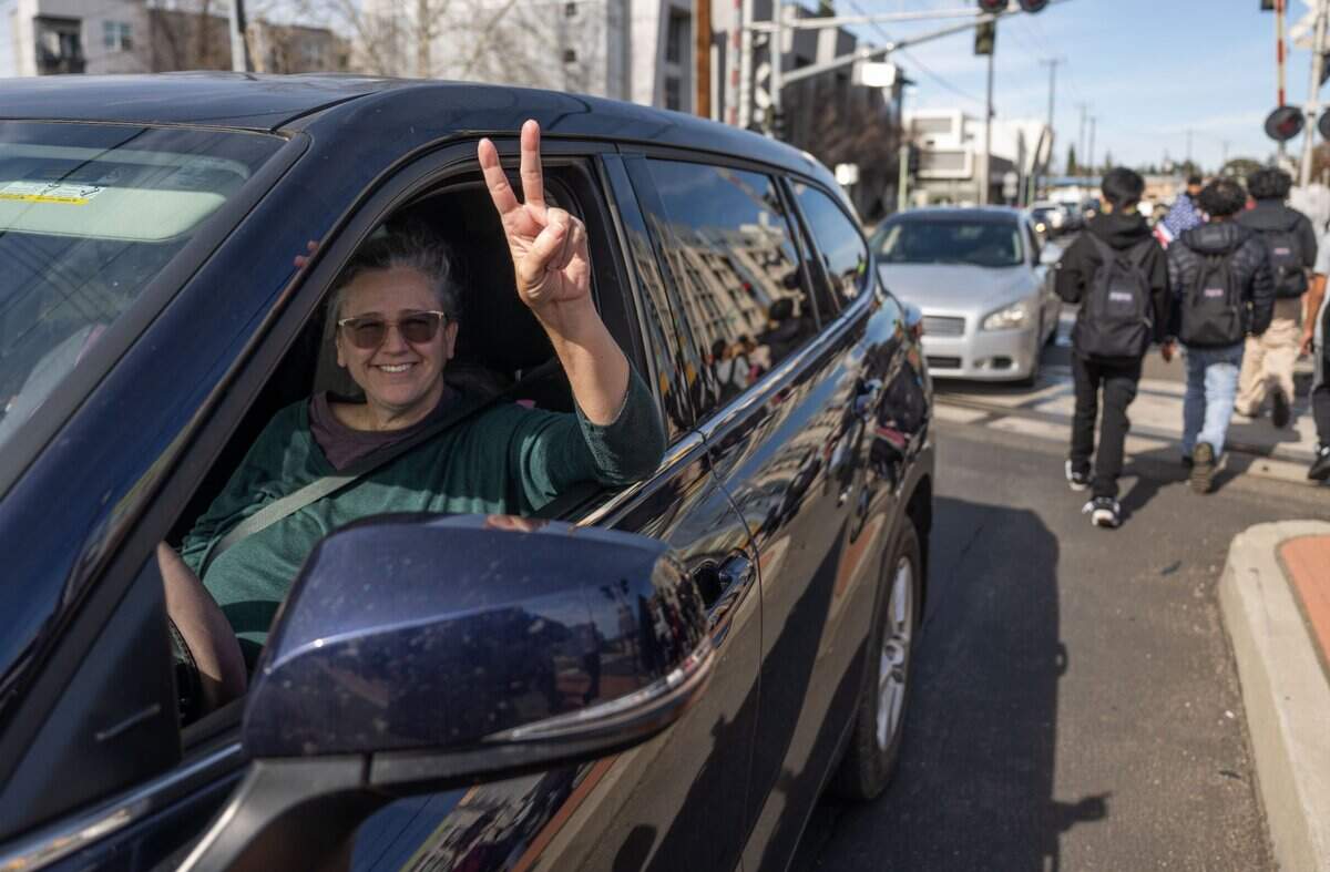 Bystander Beth Pearsall, of Sacramento, flashes a peace sign as students from Hiram Johnson High School stage a walkout Tuesday to protest President Donald Trump and his adminstration. “I like that they’re being active. I like that they’re speaking the truth. I love that they’re fighting for something they believe in and I think when we see people like them we promote peace,” she said.