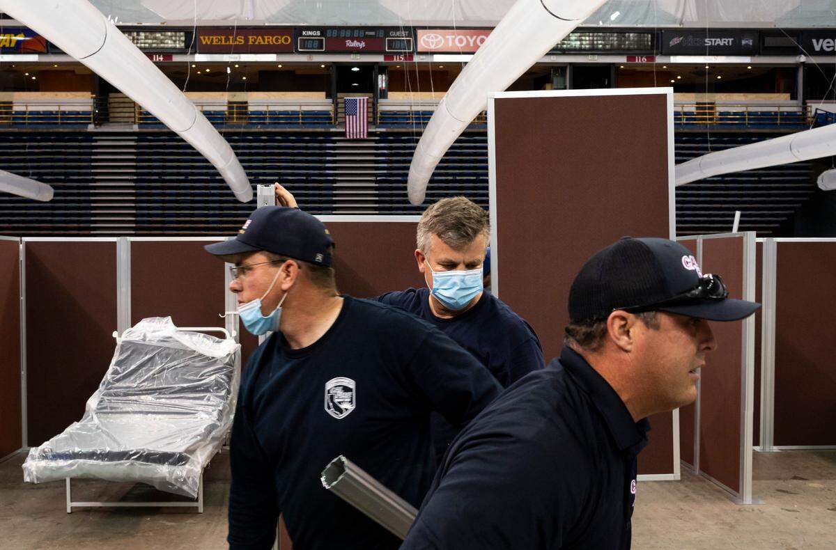 Dan McNamara, center, with San Ramon Valley Fire Team 5, works on partitions at the Sleep Train Arena alternate care facility Saturday, April 18, 2020, in preparation for opening Monday as a surge facility to combat COVID-19 in the Sacramento region.