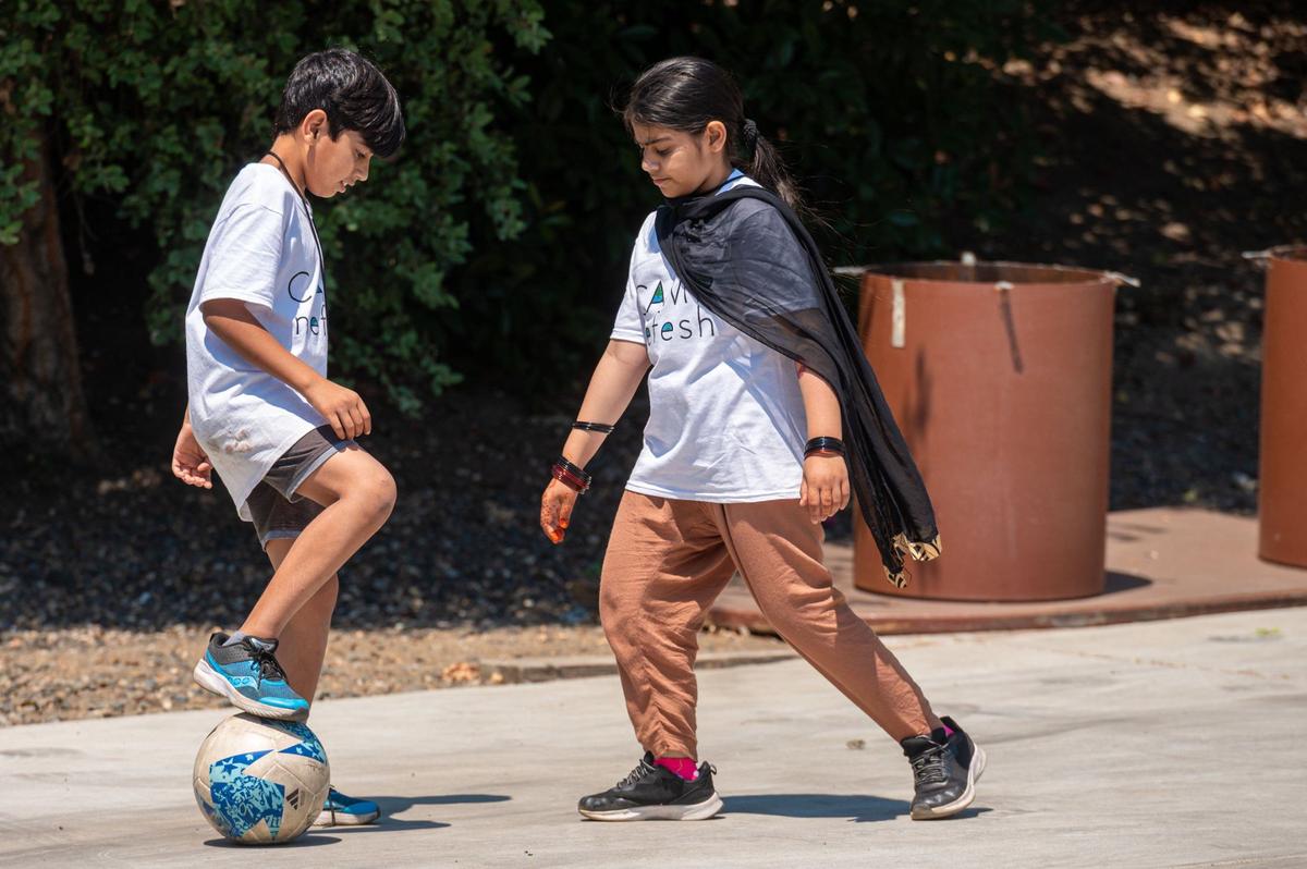 Siblings Abuzaid Rahmani, 9, and Zenat Rahmani, 10, play soccer together at Camp Nefesh in Sacramento on June 19, 2024. The Rahmani family came to Sacramento from Afghanistan in 2019.