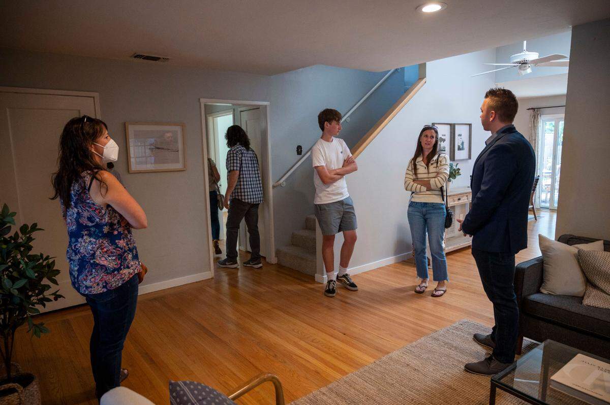 Dylan Williams, right, an agent with House Real Estate, talks with people at an open house in East Sacramento on Saturday. The four-bedroom house is offered at $995,000 and features a studio apartment above the two-car garage.