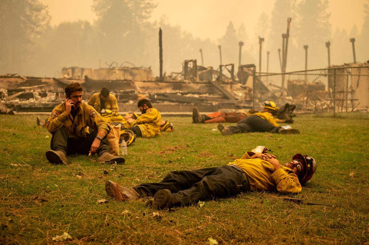 A Cal Fire crew takes a break in the grass next to Berry Creek Elementary School which was burned during the Bear Fire on Sept. 9, 2020.