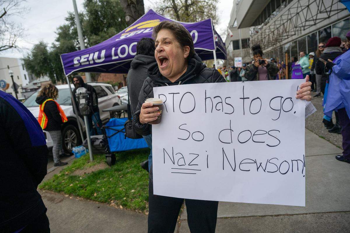 Francesca Wander holds a sign outside the CalHR office in Sacramento on Wednesday, March 12, 2025, as she joins hundreds protesting Gov. Gavin Newsom’s order directing them to return to their offices four days a week.