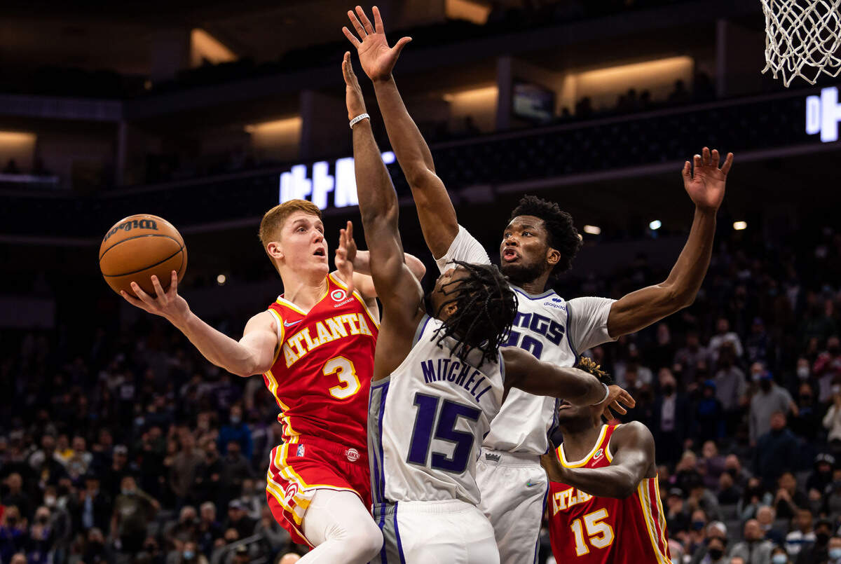 Atlanta Hawks guard Kevin Huerter (3), left, goes up for two points against Sacramento Kings guard Davion Mitchell (15), center, and center Damian Jones (30) during the fourth period of the Hawks’ win at the NBA basketball game Wednesday, Jan. 5, 2022, at Golden 1 Center in Sacramento.