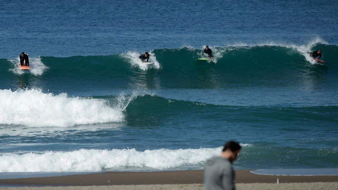 Surfers ride a wave at Ocean Beach in San Francisco, Saturday, March 21, 2020. A California surf school owner was detained at the U.S.-Mexico border in Tijuana on suspicion of killing his two young children, officials said.