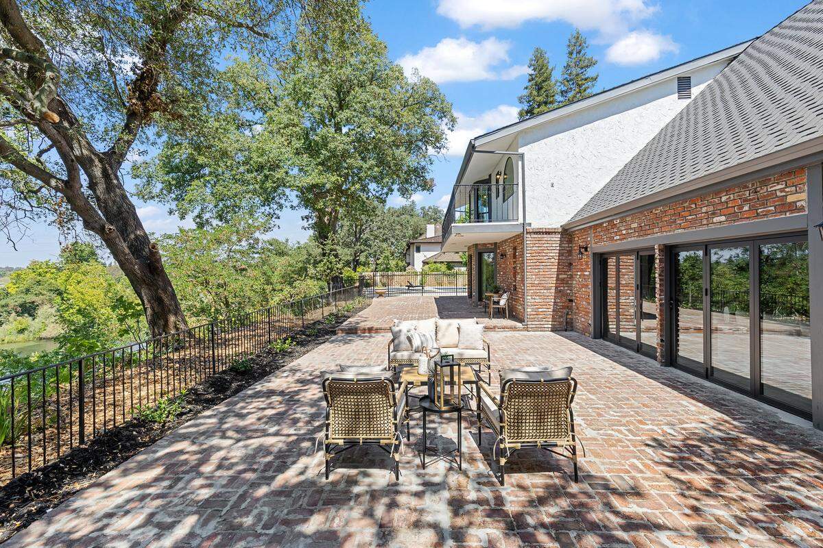 The magic unfolds outdoors — folding glass doors open the grand room to an expansive riverfront patio and modern pool, delivering seamless indoor-outdoor living with panoramic water views.