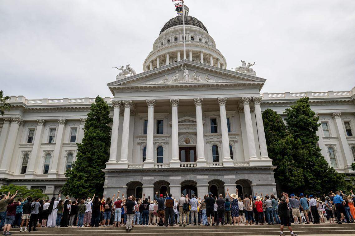 Members of the California Family Council, the California Catholic Conference and others raise hands in prayer at a Christian prayer vigil outside the California Capitol on Monday, June 5, 2023. The event was in response to ceremonies on the Senate and Assembly floors honoring a member of the Sisters of Perpetual Indulgence for LGBTQ Pride Month. The religious groups accuse the drag nuns of mocking Christianity and Catholicism.